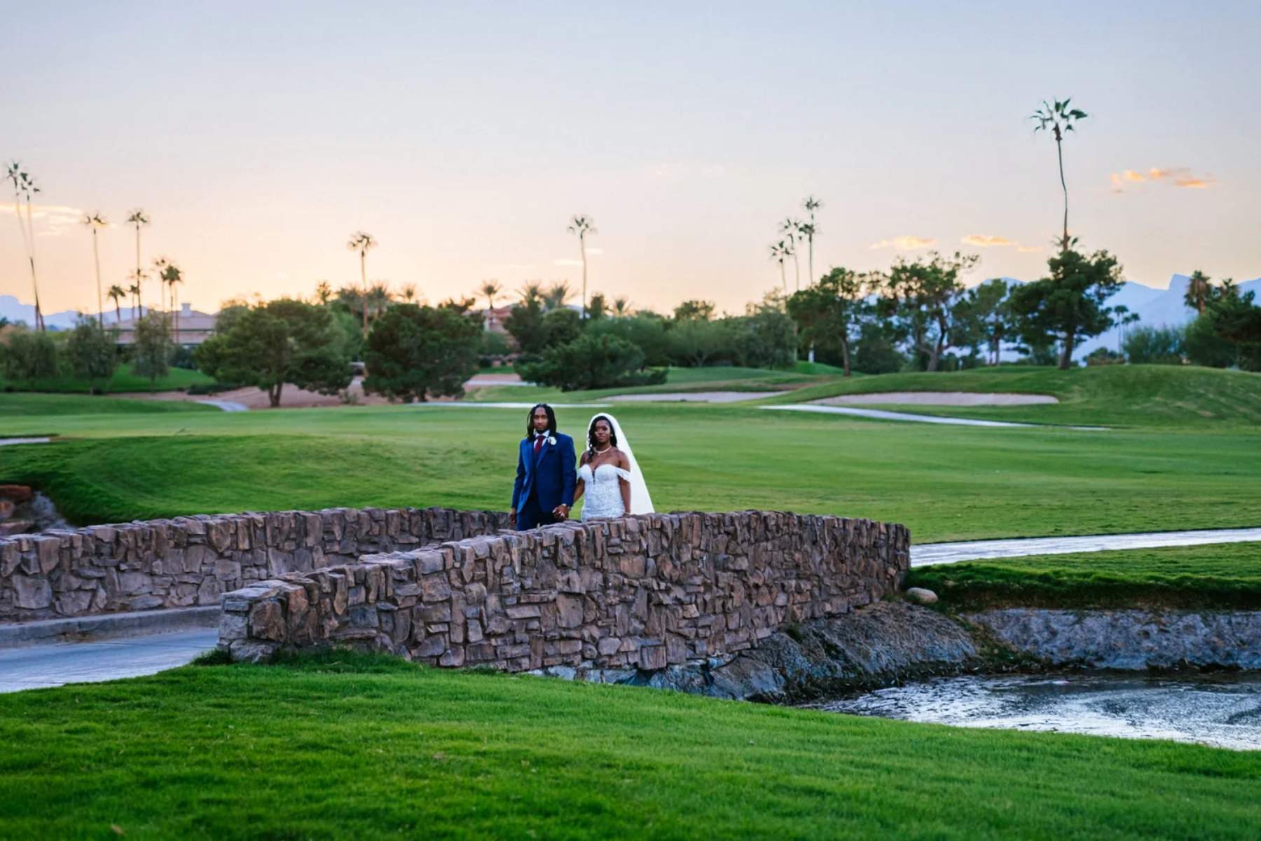 Bride and groom on a golf course bridge at sunset